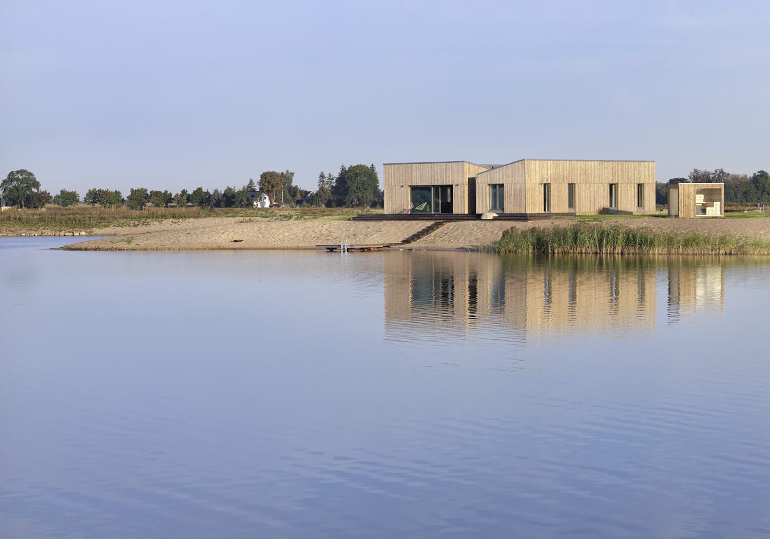 Modernes Ferienhaus am Seeufer mit Holzfassade und großer Glasfront, direkt am Wasser gelegen.